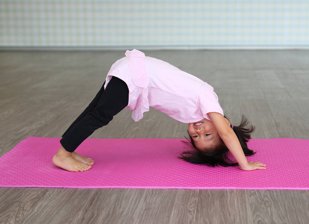 Cute toddler girl practicing yoga and doing exercise - Foto, immagini