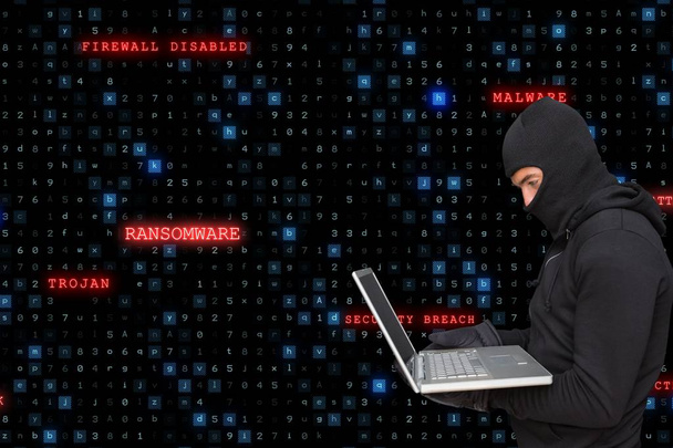 Sied vista de cibercriminoso vestindo um capuz está cortando de um laptop contra código de matriz chuva backgr
 - Foto, Imagem