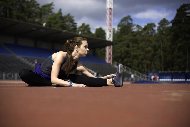 Athletic woman stretching her muscles before jogging on track - Foto, Imagem