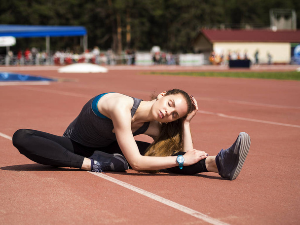 Mulher atlética esticando os músculos antes de correr na pista
 - Foto, Imagem
