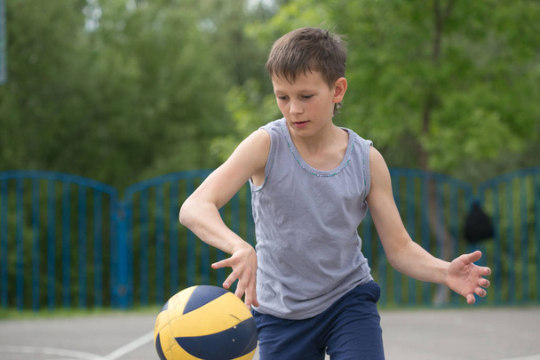Adolescente em uma camiseta e shorts brincando com uma bola
 - Foto, Imagem