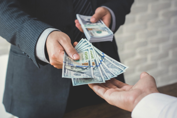 Businessman giving or paying money to a man - Фото, зображення