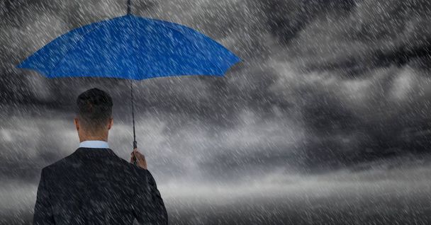 Back of business man with umbrella against storm clouds with rain - Photo, image