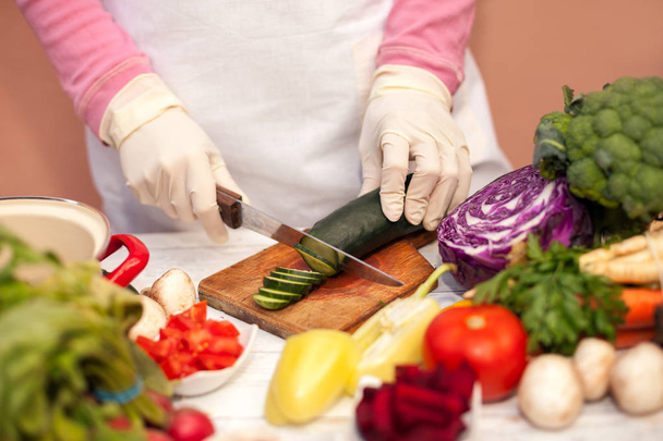 Donna con guanto bianco taglio cetriolo in cucina
 - Foto, immagini