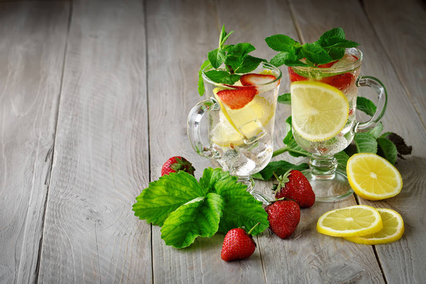 Fresh summer healthy drink with lemon and strawberries with ice. - Фото, изображение