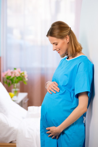 Terhes nő fogdossa a hasát - Fotó, kép