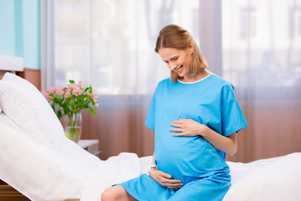 Zwangere vrouw raakt haar buik aan - Foto, afbeelding