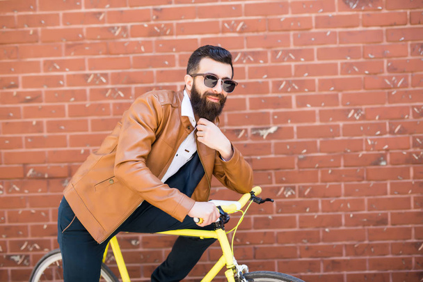 Cool jovem hipster barbudo além de uma bicicleta fixie na parede de tijolo na rua
 - Foto, Imagem