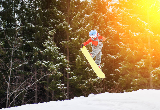 Junge springt und hält eine Hand auf dem Snowboard - Foto, Bild