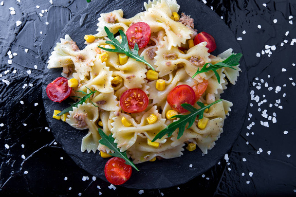 スレート板チェリー トマト、ツナ、コーン、ルッコラのパスタのサラダ。平面図です。イタリア料理. - 写真・画像