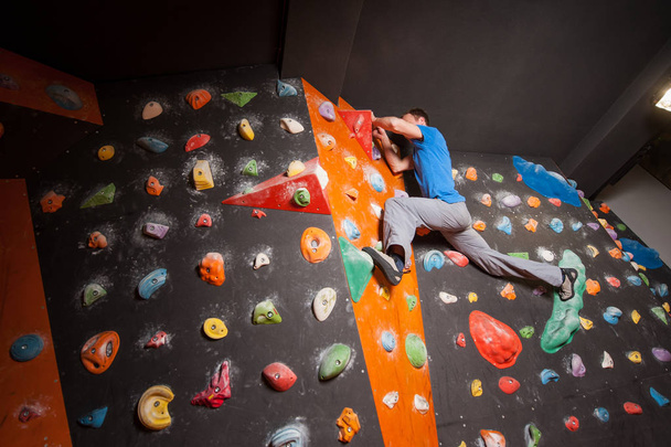 Strong male climber on boulder climbing wall indoor - Photo, image