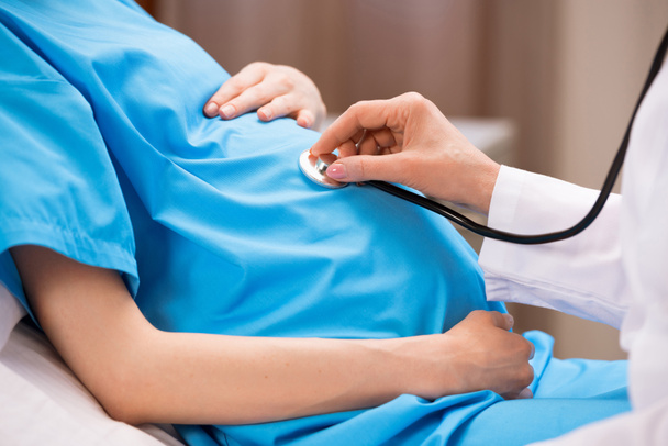 Doctor listening belly of pregnant woman  - Photo, Image