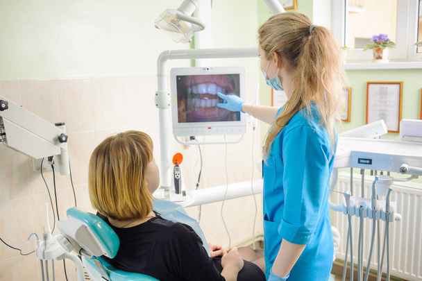dentista feminina mostrando fotografia de dentes no computador para paciente
 - Foto, Imagem