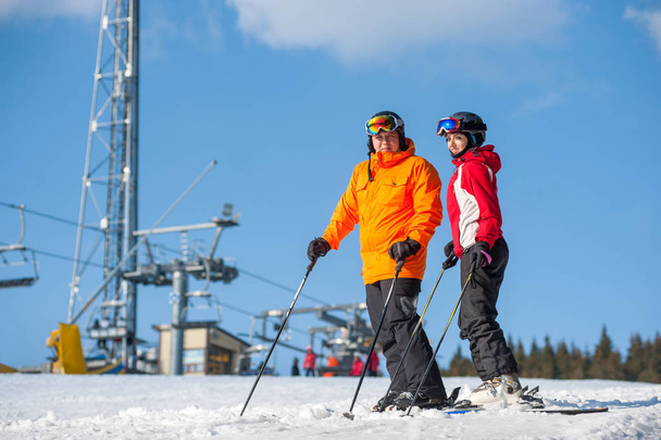 冬のリゾート地でスキーを持つ男と女のスキーヤー - 写真・画像