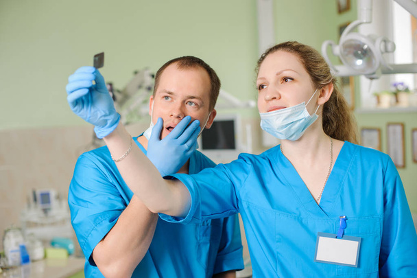 женщина-стоматолог показала рентген коллеге-мужчине в стоматологической клинике
 - Фото, изображение
