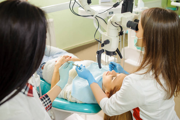 女性歯科医の歯科医のオフィスで顕微鏡を用いた齲蝕の治療 - 写真・画像