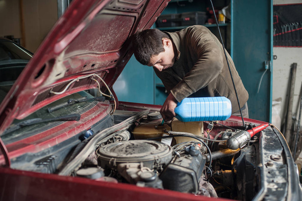 Mechanic man worker pouring antifreeze in the cooling system - Photo, Image