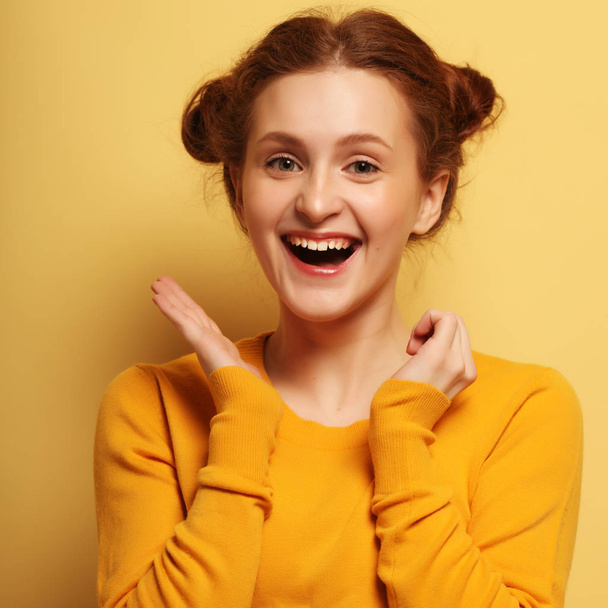 Young cute smiling redhair girl on yellow  background - Фото, изображение