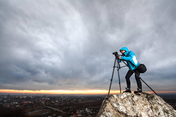 Fotógrafa con cámara en trípode en la roca grande
 - Foto, Imagen