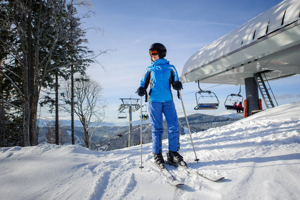 Female skier against ski-lift and winter mountains background - Photo, Image