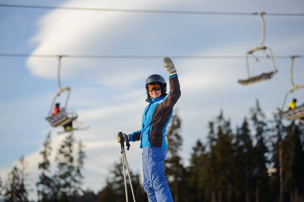 Mulher esquiadora contra ski-lift e floresta em um dia ensolarado
 - Foto, Imagem