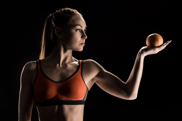 pensive sporty girl holding orange - Fotografie, Obrázek