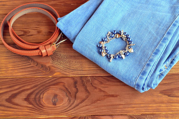 Jeans, pulseira, cinto em fundo de madeira com espaço de cópia para texto
  - Foto, Imagem