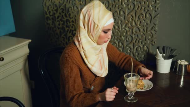 Uma muçulmana moderna come sobremesa e bebe um coquetel de chocolate em um café
 - Filmagem, Vídeo