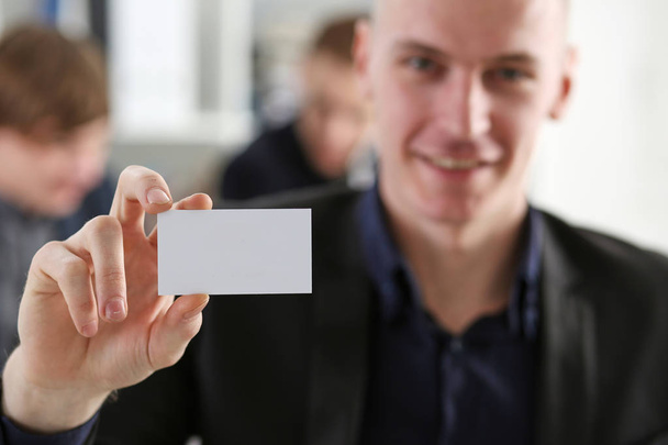 El hombre de negocios sonriente con traje tiene en la mano la tarjeta de visita
 - Foto, Imagen