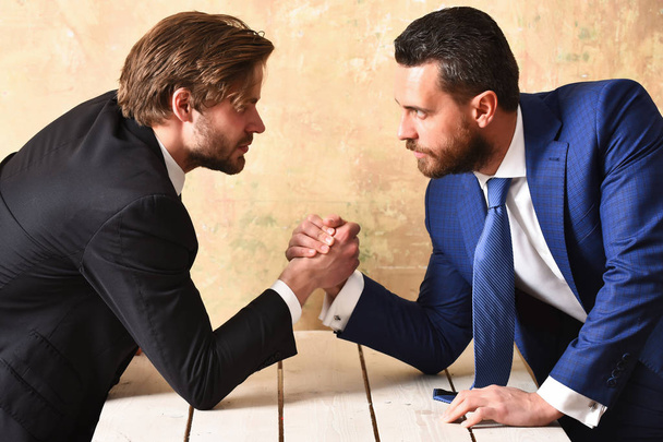 Business rivalry in office. Arm wrestling between two businessmans - 写真・画像