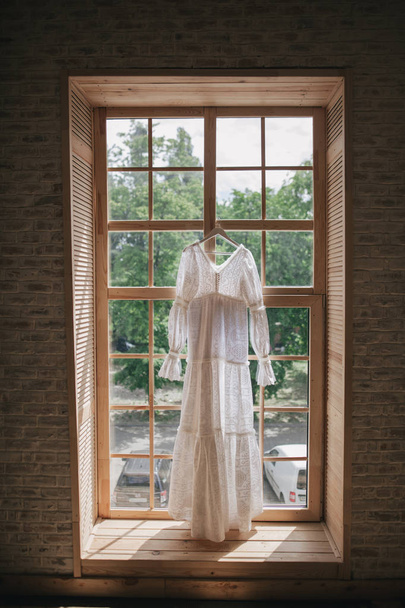 vintage wedding dress hanging on window - Zdjęcie, obraz