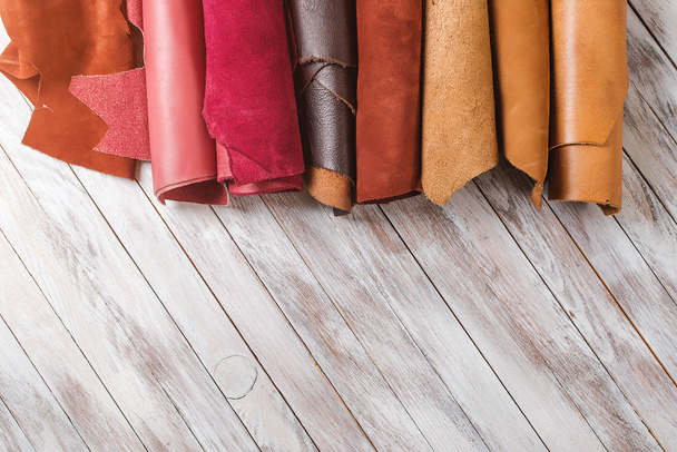 Multicolored leather in rolls on wooden background. - Foto, Imagem