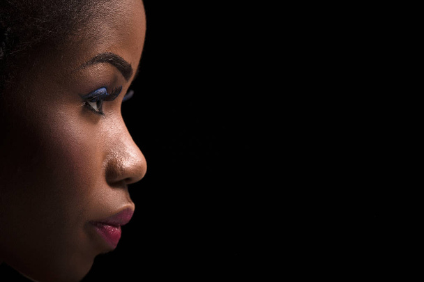 Side view portrait of dark skinned model on a black background. - Foto, Imagen