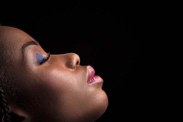 Side view portrait of dark skinned model on a black background. - 写真・画像