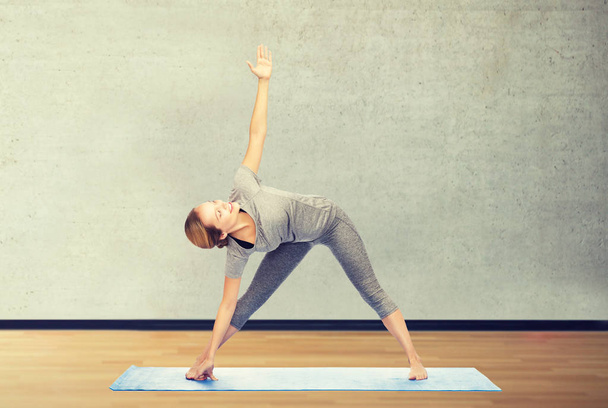 femme faisant pose triangle yoga sur tapis
 - Photo, image