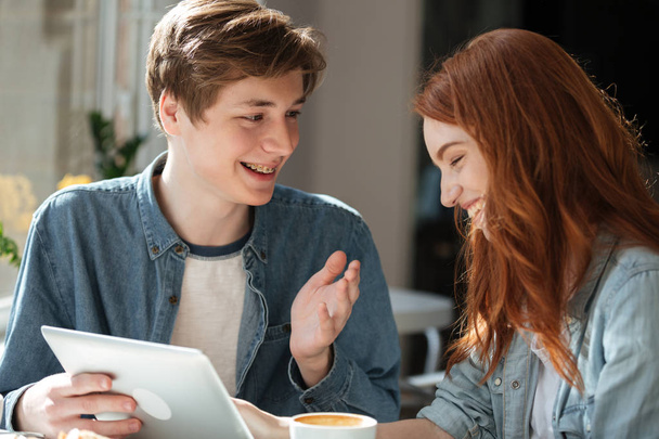 Young smiling couple talking while using tablet - Fotografie, Obrázek