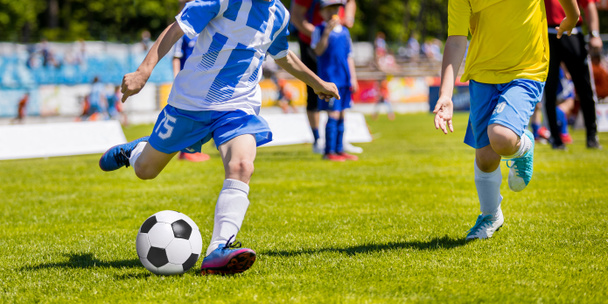 Τρέχει ποδοσφαιριστές ποδόσφαιρο της νεολαίας. Αγόρια κλοτσιές αγώνα ποδοσφαίρου. Παιδιά ποδοσφαιριστές τρέχει μετά την μπάλα. Παιδικά Αθλητικά μονομαχία - Φωτογραφία, εικόνα