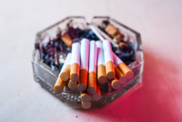 Un tas de cigarettes filtrées dans un cendrier sale avec des mégots de cigarette
, - Photo, image