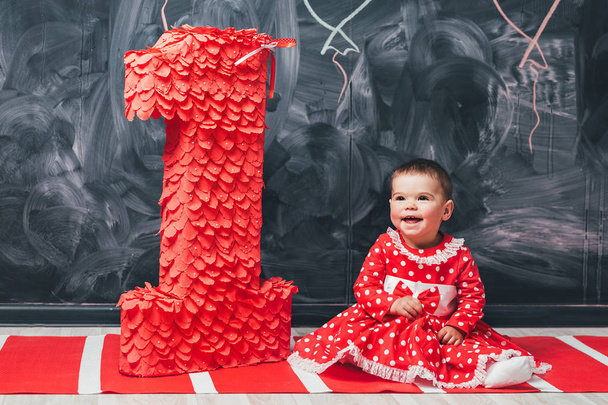 幼児の大きな図 1 近くに座って白い円に赤いドレスの女の子。彼女の誕生日に 1 歳女の子 - 写真・画像