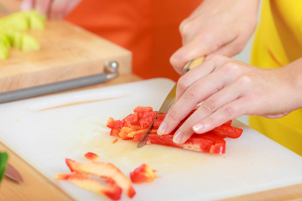 Woman preparing vegetables salad slicing red pepper - Fotó, kép
