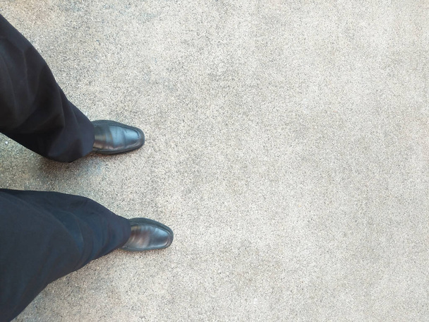 чоловік з чорним взуттям, що стоїть на фоні конкретної текстури
 - Фото, зображення
