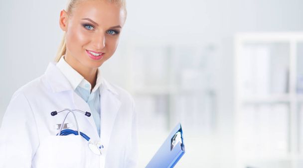 Χαμογελαστή γυναίκα γιατρός με ένα φάκελο με στολή στέκεται σε hosp - Φωτογραφία, εικόνα