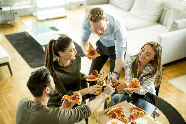 Vrienden eten van pizza in het moderne interieur - Foto, afbeelding