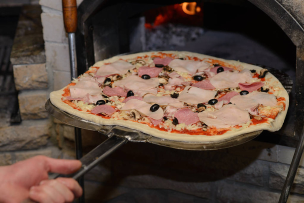 process of making delicious pizza with ham, cheese and mushrooms in a pizzeria - Photo, Image