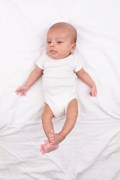 Newborn baby on white sheet - Фото, изображение