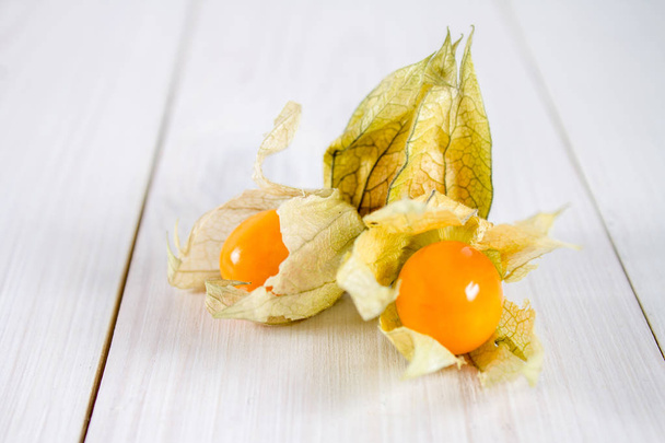 Exotic berries physalis on a white wooden table. - Zdjęcie, obraz