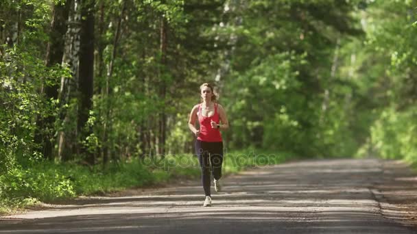giovane donna Jogging nella foresta estiva. la ragazza fa sport nella natura. il modello corre verso la fotocamera
. - Filmati, video