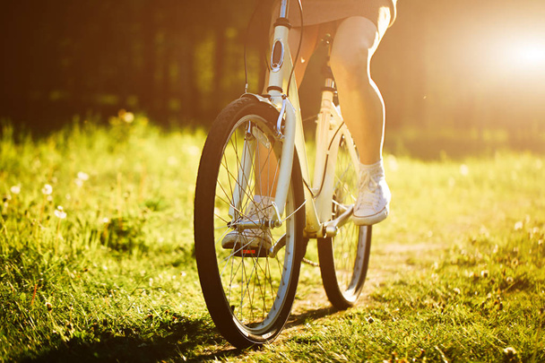 Vicces lány vezetés szabadtéri. A hangsúly a kerékpár. Napsütéses nyári életmód fogalma. Nő a ruha és kalap területen pitypang. Női ride a parkban. Könnyű fénykép hatása a szöveg. Copyspace design. - Fotó, kép