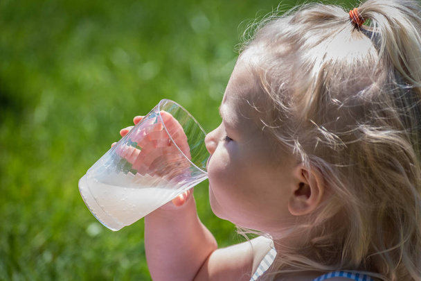 durstiges kleines Mädchen trinkt im Sommer eine Tasse Limonade - Foto, Bild
