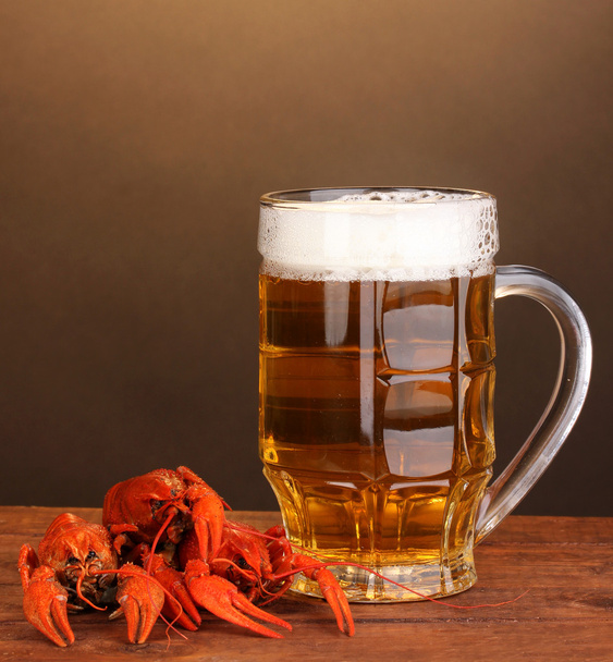 Tasty boiled crayfishes and beer on table on brown background - 写真・画像
